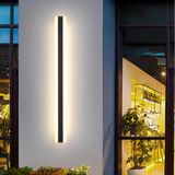 Modern outdoor wall light installed on exterior wall beside entrance door