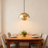 Gold double-shade pendant light above a side table beside an armchair