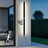 Minimalist black outdoor long LED wall light with motion sensor mounted beside a modern front doo