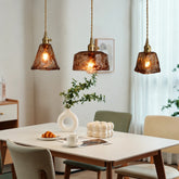 Three amber glass pendant lights above a dining table in a mid-century interior
