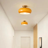 Two orange glass ceiling lights with gold-finish bases installed along a hallway