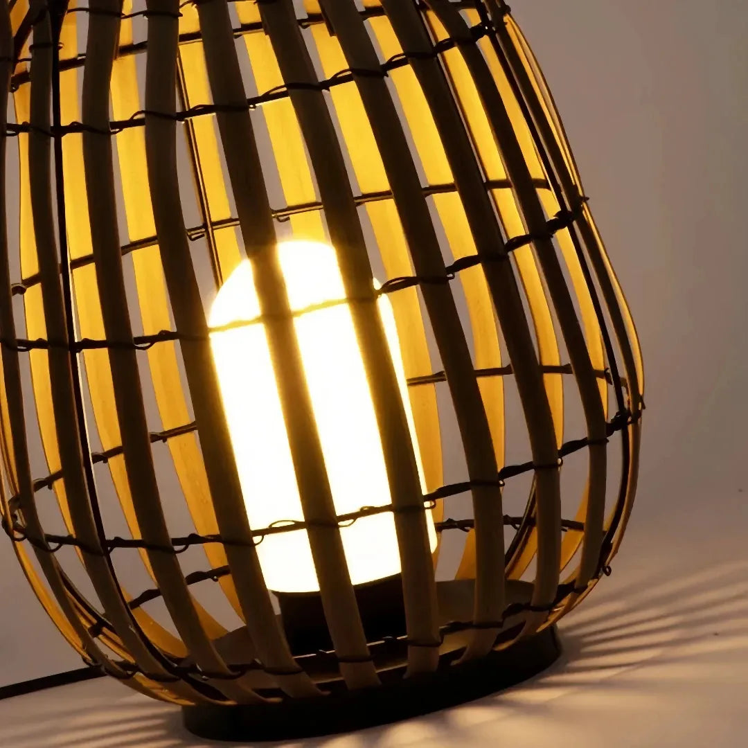 Close-up of warm LED light shining through the woven rattan shade of an outdoor floor lantern