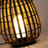 Close-up of warm LED light shining through the woven rattan shade of an outdoor floor lantern