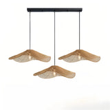 Three wave rattan pendant shades suspended from a black linear ceiling bar