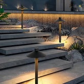 Black metal mushroom pathway light illuminating garden steps at night
