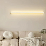 White linear LED wall light mounted horizontally above a sofa