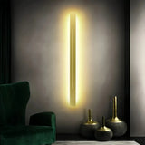 Gold linear LED wall light beside a green accent chair