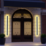 Two black vertical LED wall lights casting warm light beside an arched entrance