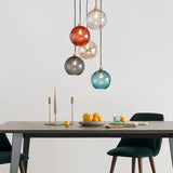 Coloured glass pendant light hanging above dining table in modern home interior