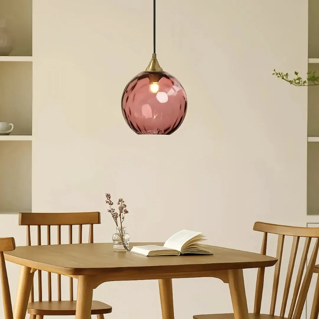 Coloured glass pendant light hanging above dining table in modern home interior