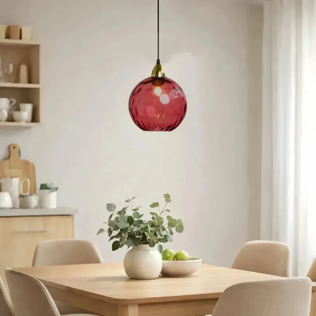 Coloured glass pendant light hanging above dining table in modern home interior