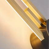 Gold two-line linear LED wall light with a dark centre mount beside framed wall art