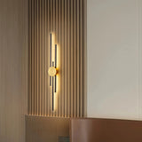 Gold two-line linear LED wall light with a black centre mount on a light wall