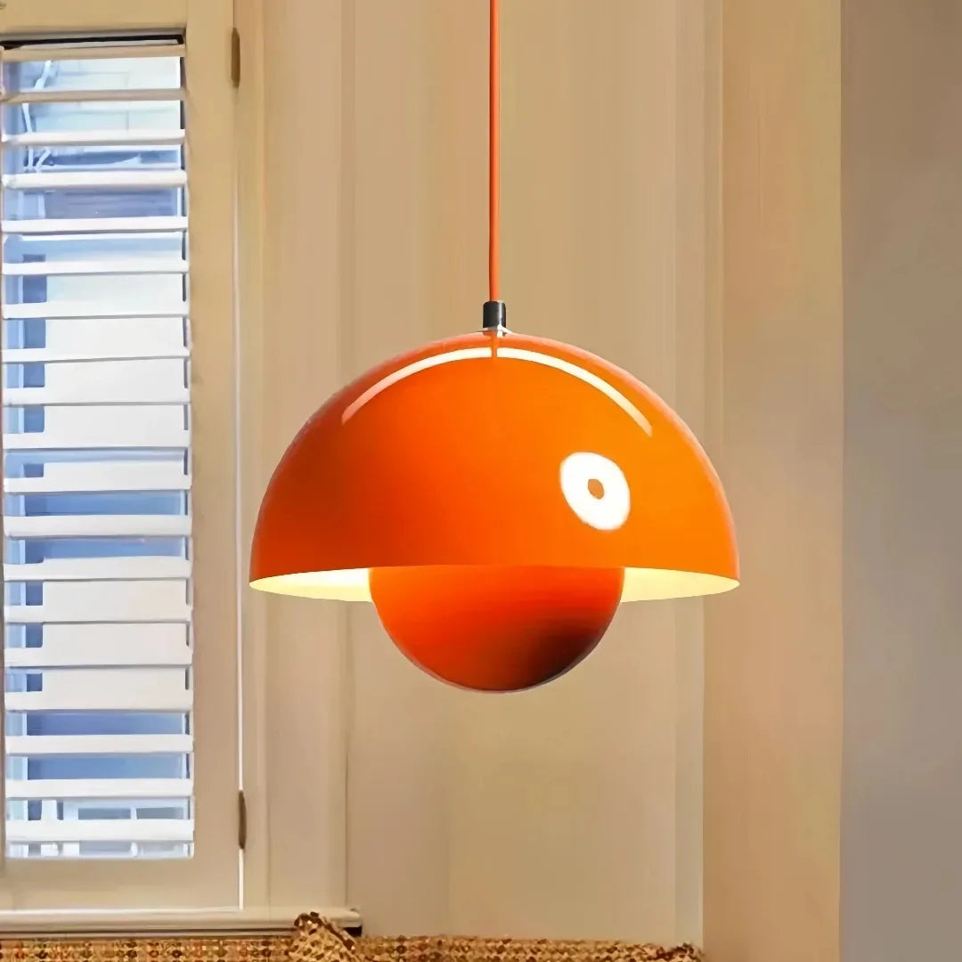 Orange double-shade pendant light in a neutral-toned dining space