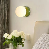 Illuminated glass globe wall light in a bedroom setting