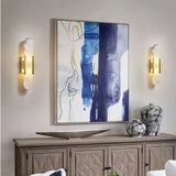 Two gold marble wall lights framing abstract artwork above a living room sideboard