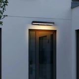 Illuminated black rectangular wall light at an exterior entrance