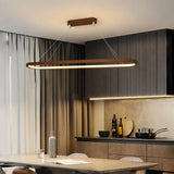 Wooden oval LED pendant above a kitchen island with dark cabinetry