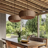 Two rattan pendant lights above a table on a covered terrace