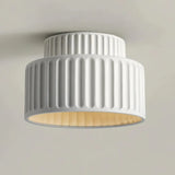 Underside view of a cream flush ceiling light with a ribbed shade