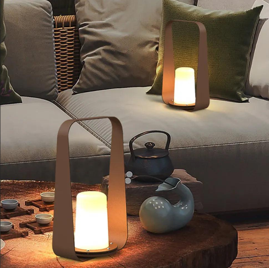 Modern lantern-style lights emit a soft glow in a cozy living room, with teacups and a wooden table, creating a tranquil and inviting ambiance.