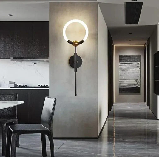 Modern wall-mounted LED wall light with black and gold finish, providing warm ambient lighting in a contemporary hallway and dining area.