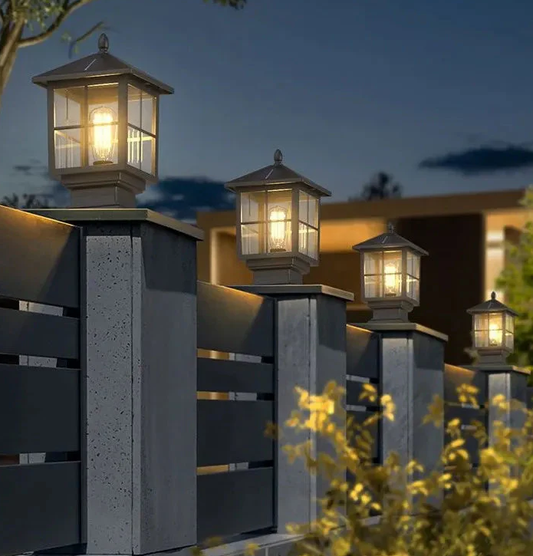 Warm-glow lantern post lights on modern fence pillars at dusk, lighting a garden boundary and adding safe, cosy kerb appeal.