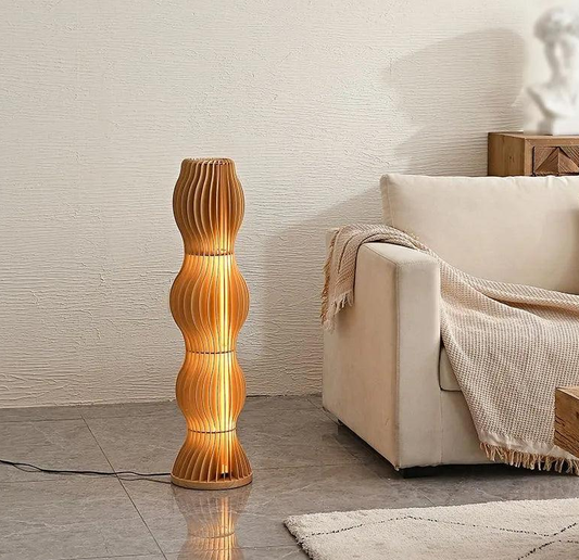 Sculptural wooden floor lamp casting warm ambient glow beside sofa in modern UK living room, perfect for cosy layered lighting.