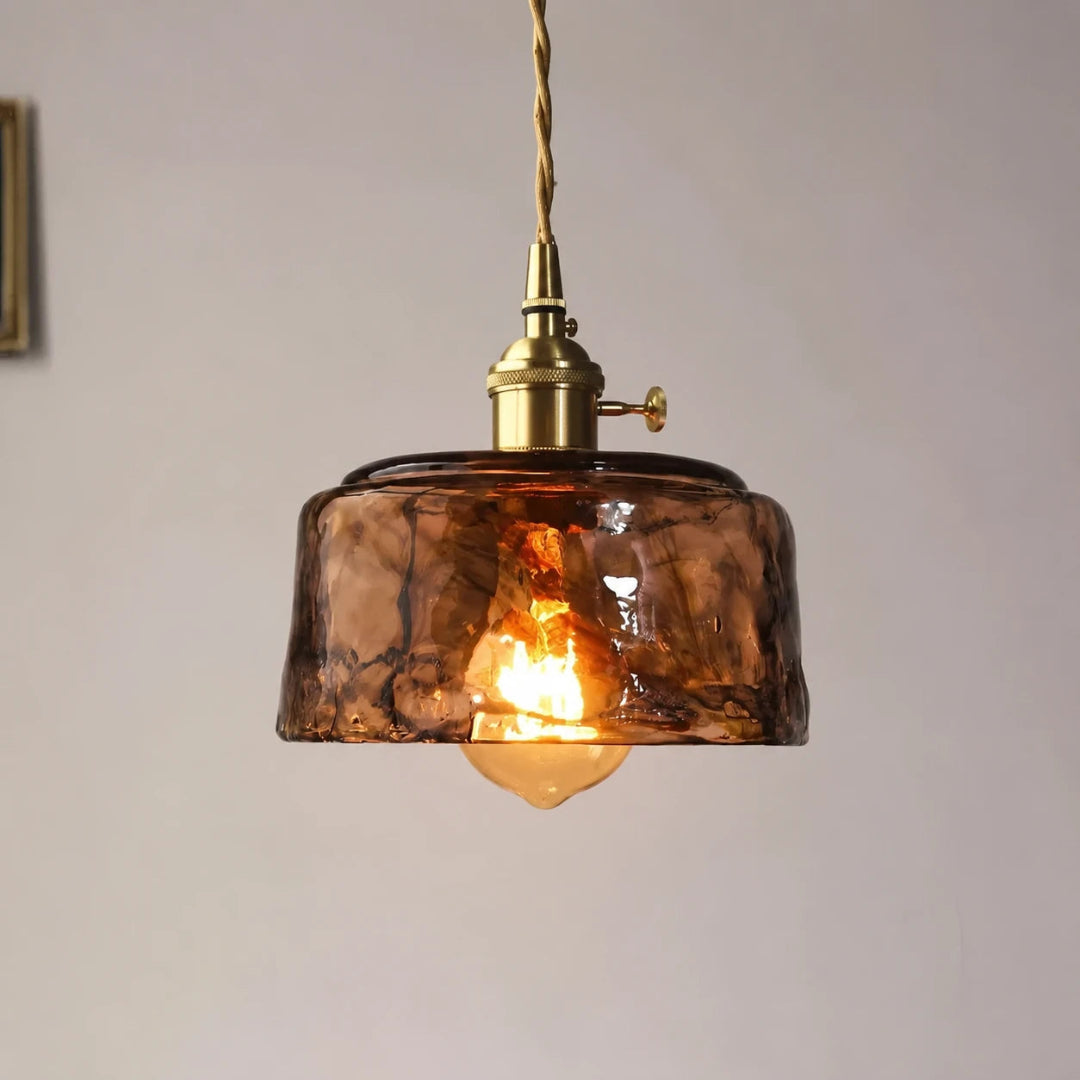 Close-up of a single amber glass pendant light with a warm glowing LED bulb