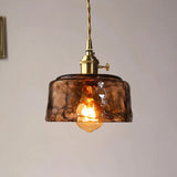Close-up of a single amber glass pendant light with a warm glowing LED bulb