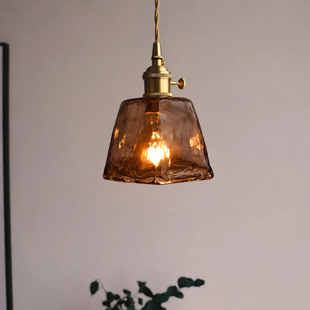 Close-up of a single amber glass pendant light with a warm glowing LED bulb