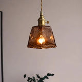 Close-up of a single amber glass pendant light with a warm glowing LED bulb