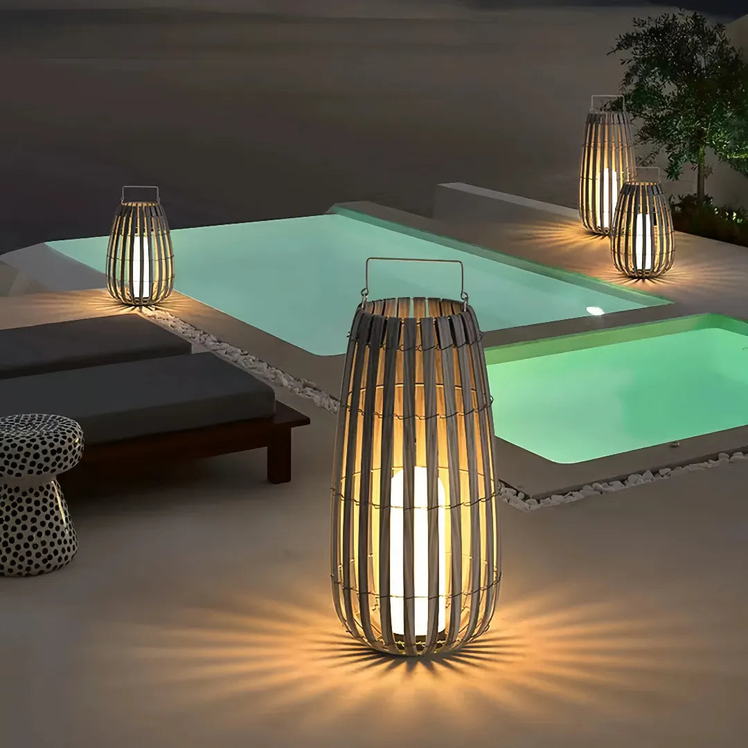 Woven rattan garden floor lanterns creating warm ambient lighting beside a swimming pool