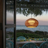 Rattan pendant light hanging above an outdoor dining table