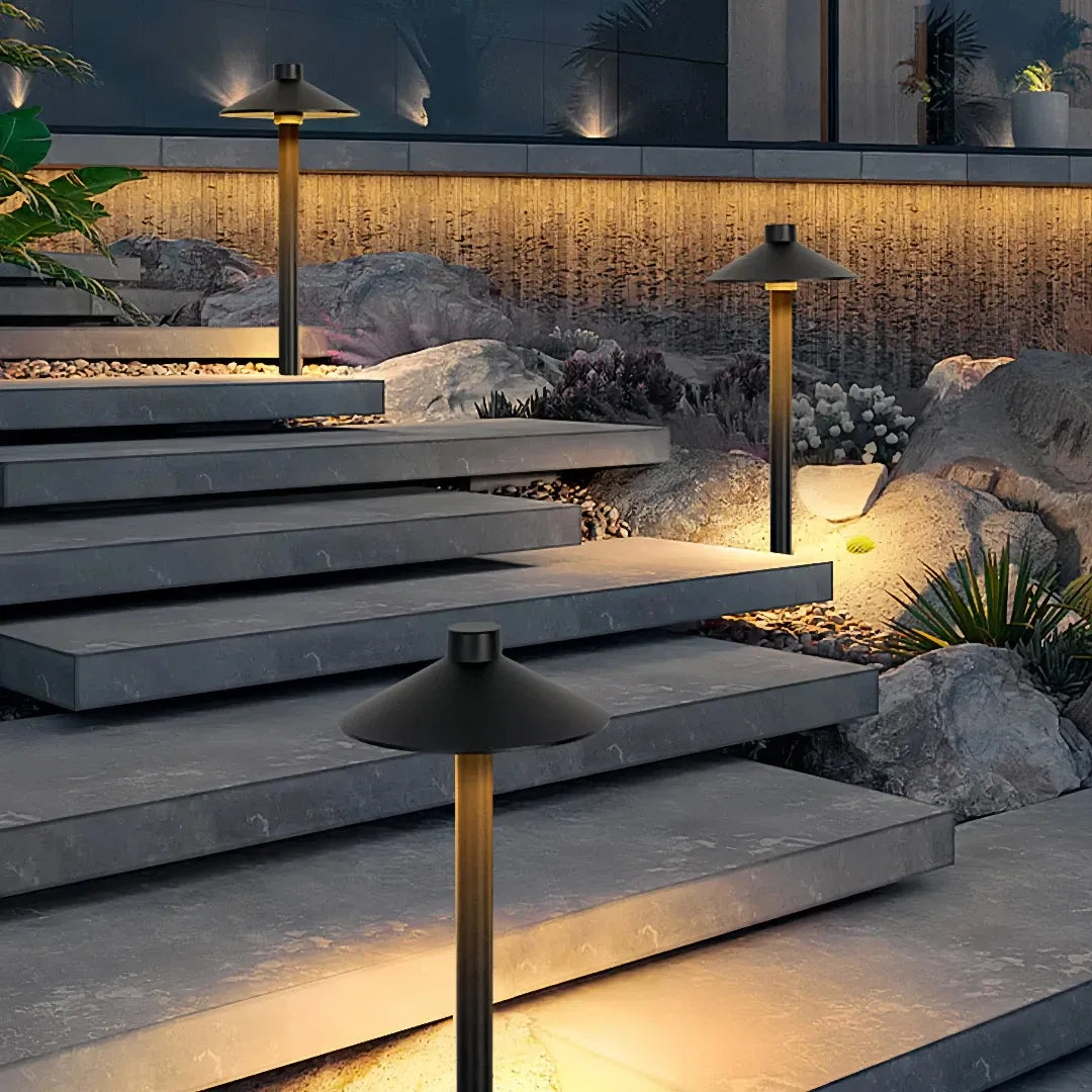 Black metal mushroom pathway light illuminating garden steps at night
