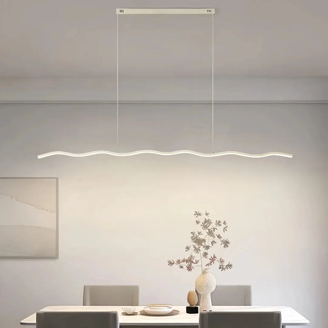 White wave linear LED pendant light above a dining table