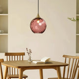 Coloured glass pendant light hanging above dining table in modern home interior