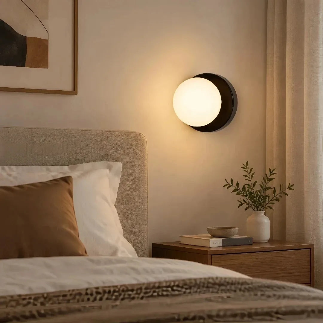 Illuminated glass globe wall light in a bedroom setting