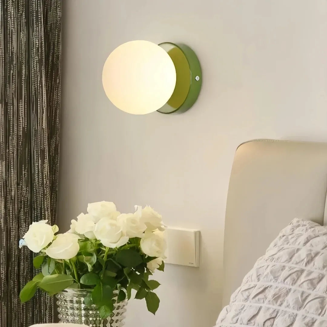 Illuminated glass globe wall light in a bedroom setting