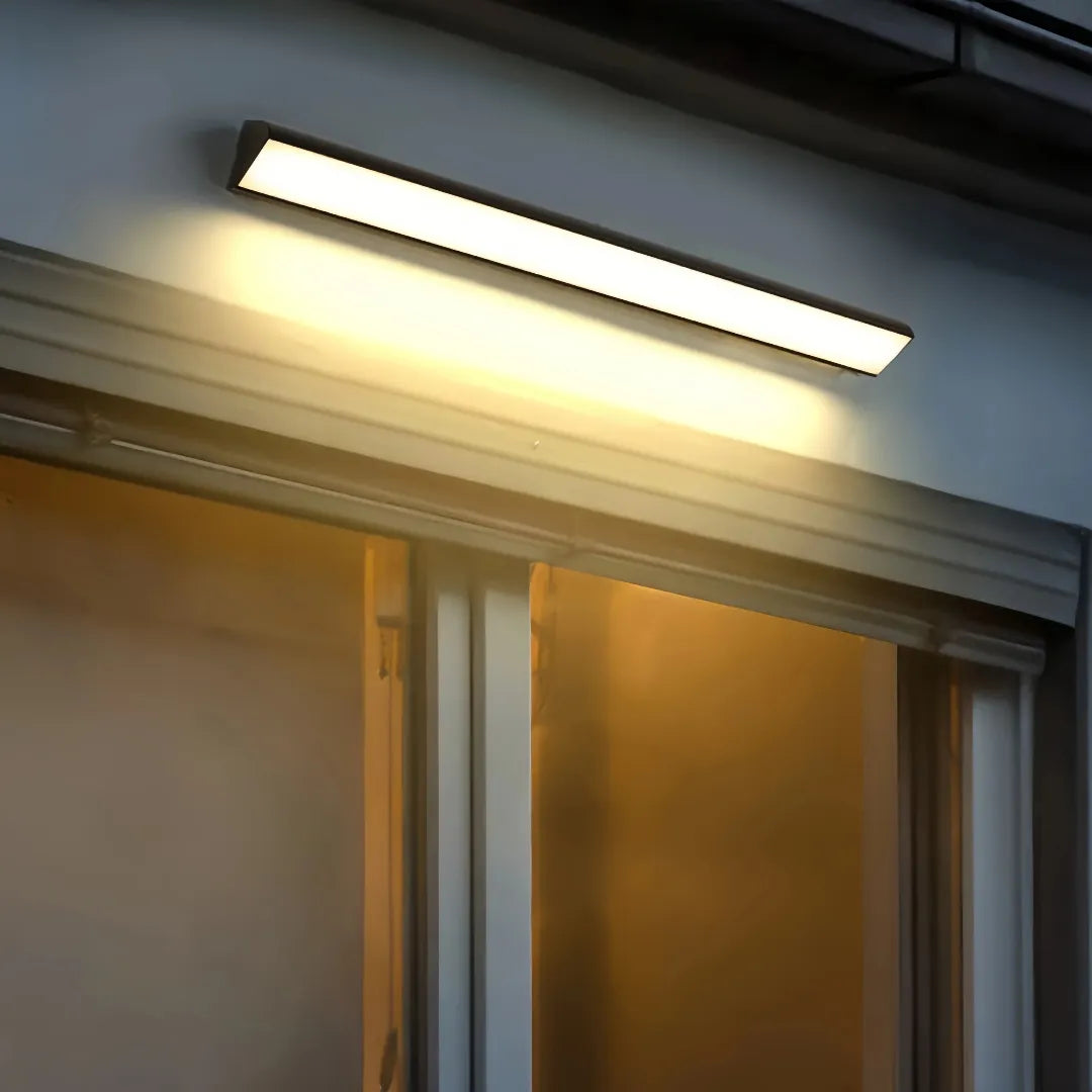 Black linear wall light casting warm light above glazed doors