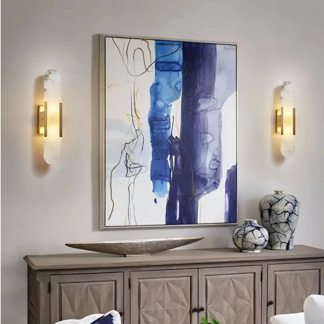 Two gold marble wall lights framing abstract artwork above a living room sideboard