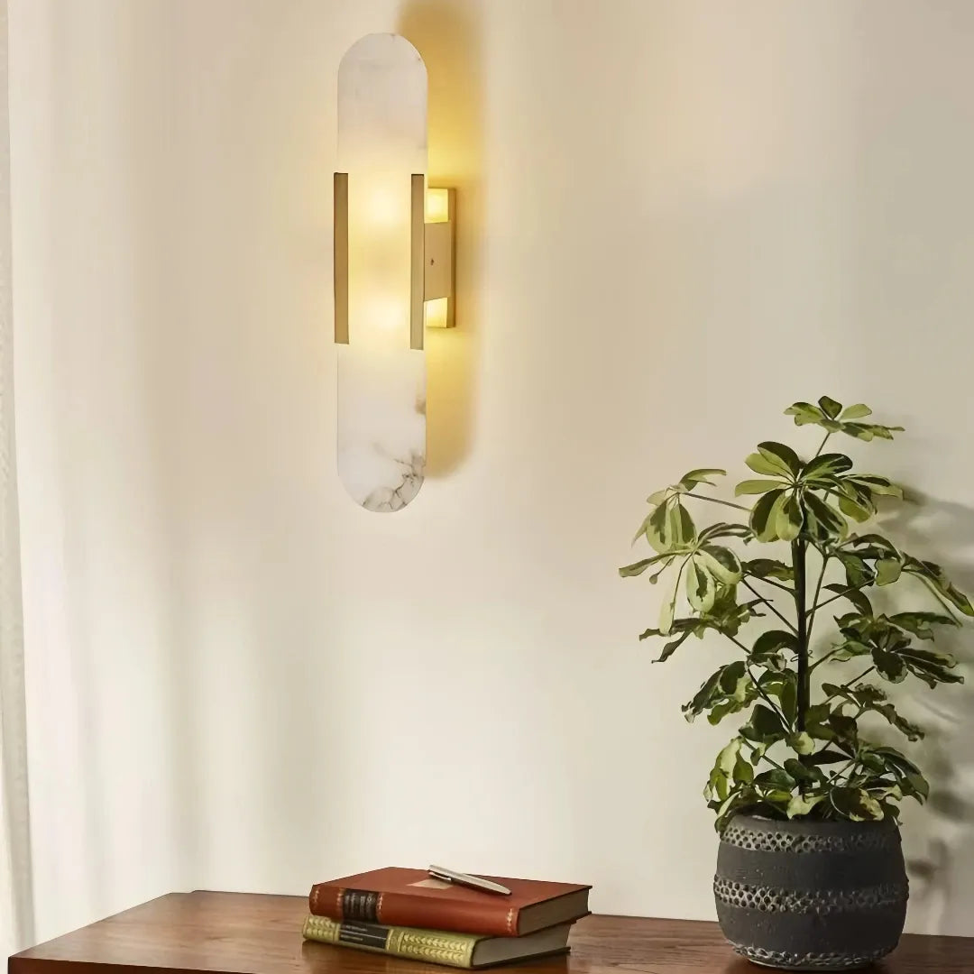Oval marble and gold LED wall sconce providing warm ambient lighting above a wooden console