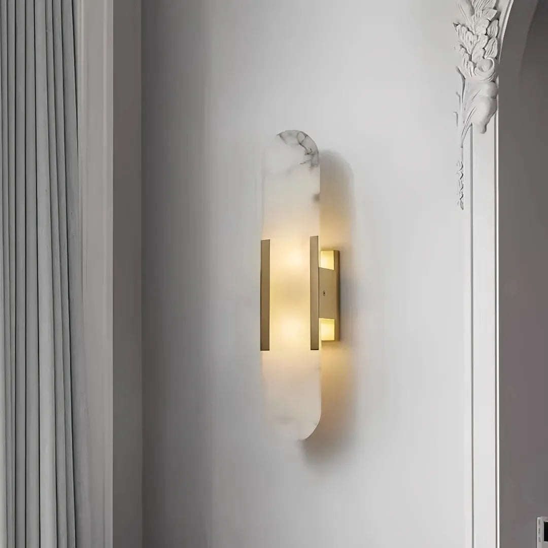 Gold oval marble LED wall light with soft warm illumination mounted on a bedroom wall