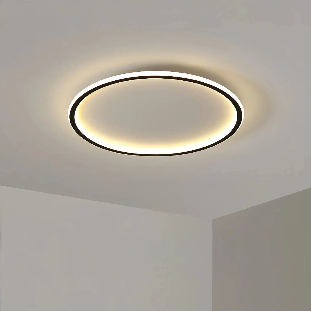 Black round flush ceiling light casting warm light over a bedroom