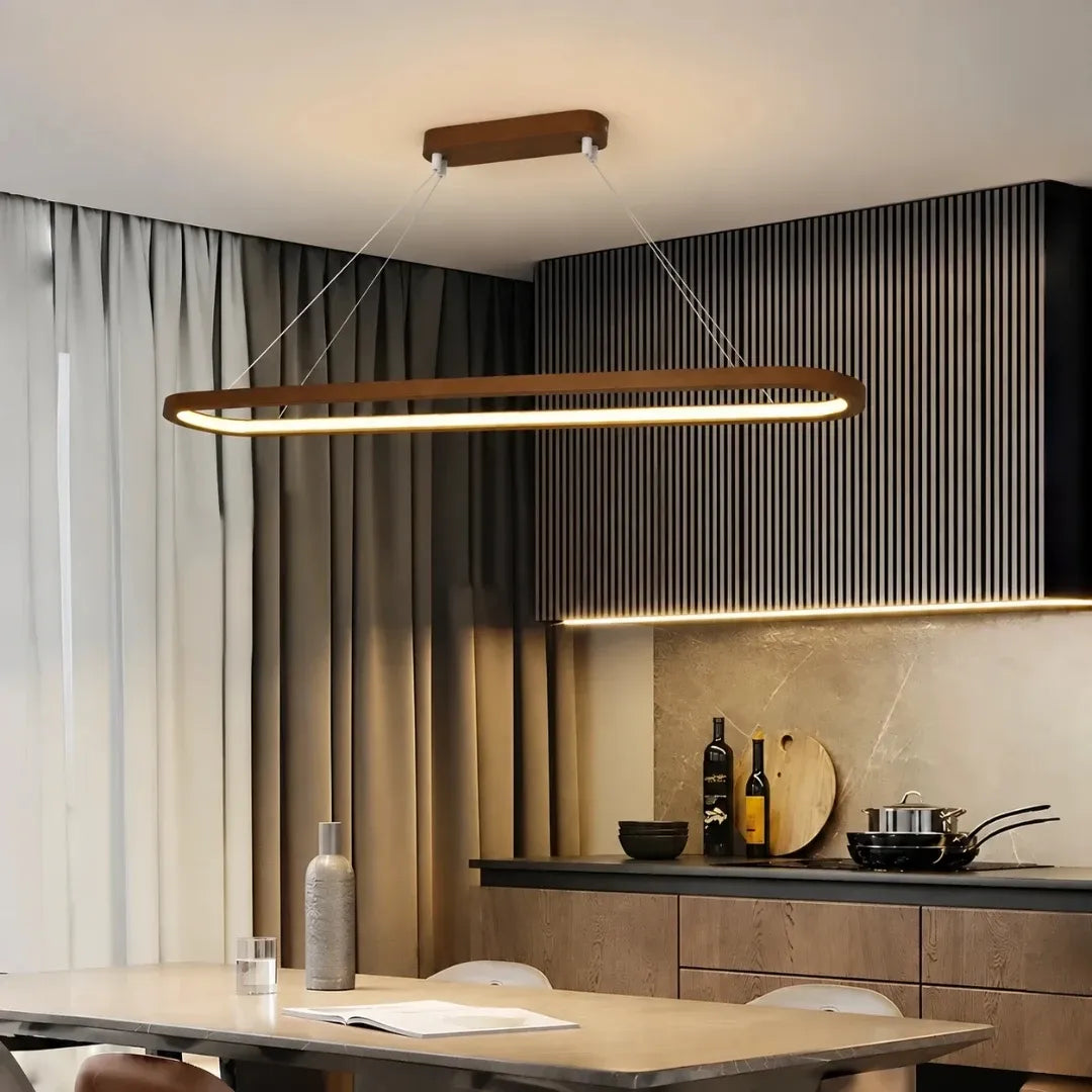 Wooden oval LED pendant above a kitchen island with dark cabinetry