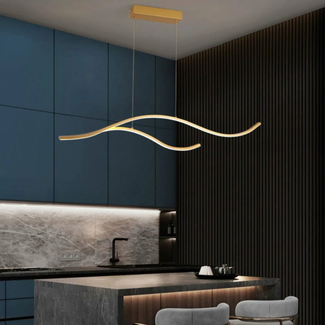 Gold wave pendant light above a wooden dining table