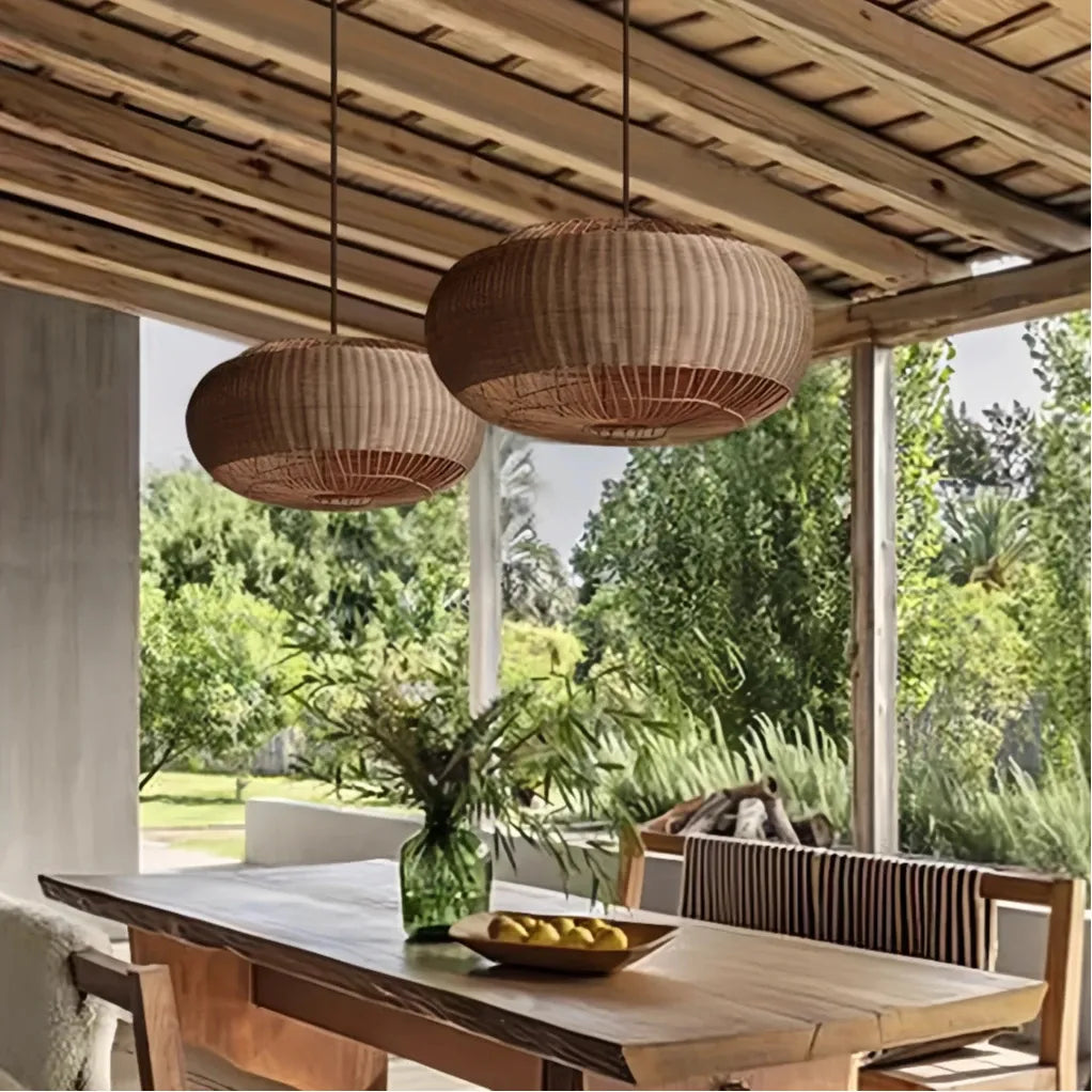 Two rattan pendant lights above a table on a covered terrace