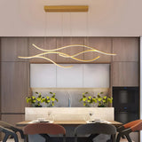 Gold wave LED pendant light above a dining table