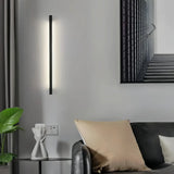Slim black LED wall light installed vertically beside a sofa